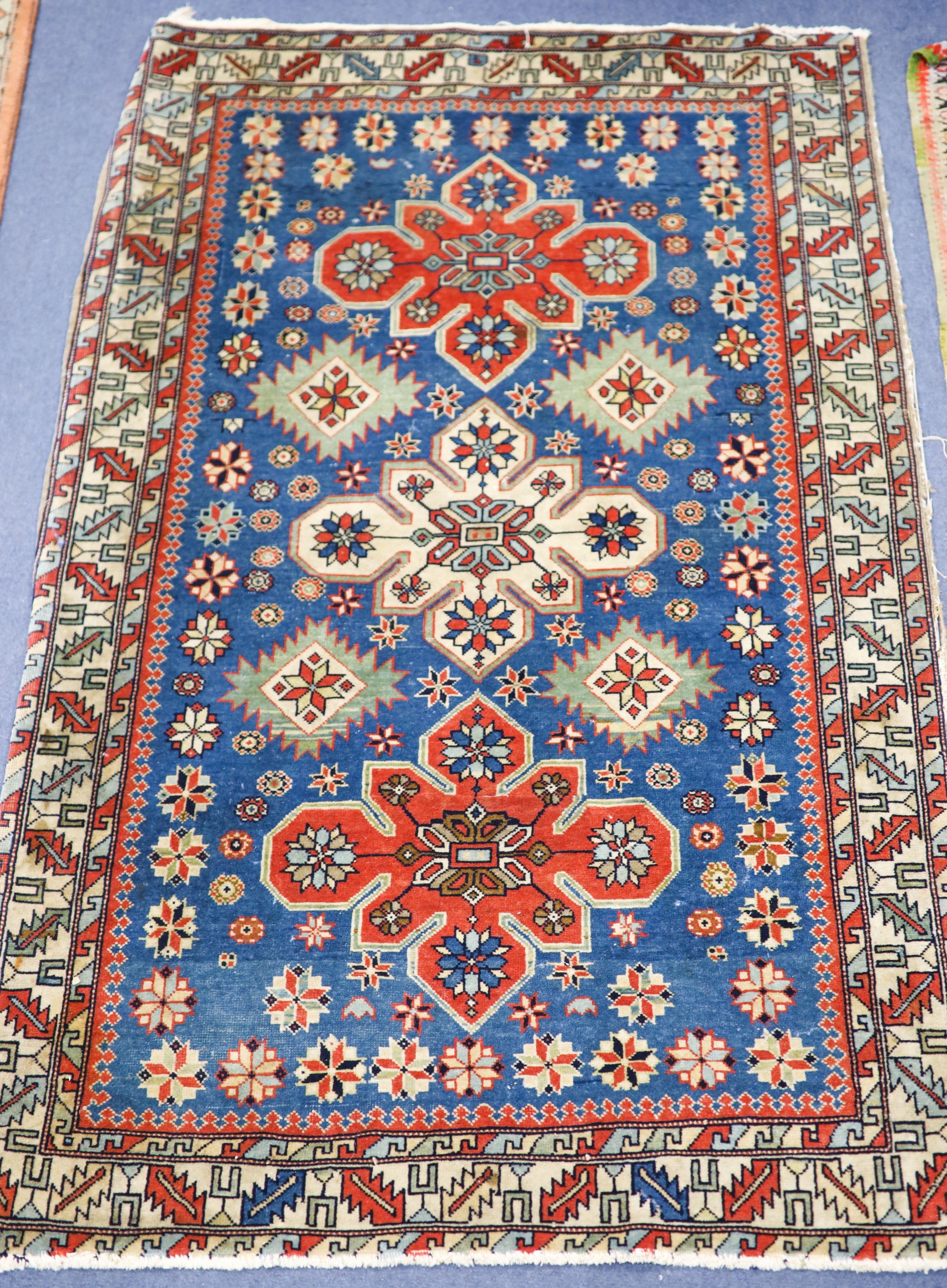 A Caucasian blue ground rug with triple medallions and geometric border, 144 x 89 cm.